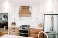 A beautiful two-toned kitchen remodel with white painted cabinets and warm stained wood. An independent wood hood features a modern style.