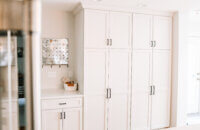 A wall of white painted cabinets and a drop-zone space with an organizational planner.