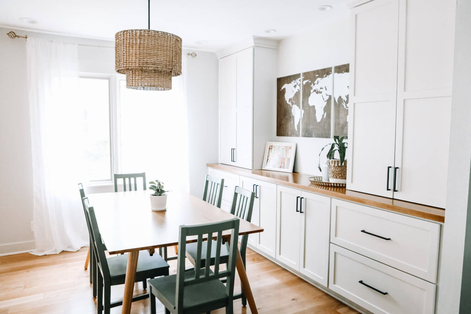 A dining room with built-in white painted cabinets with a wood top counter and 2 tall towers for additional dining room storage and space for homework supplies.