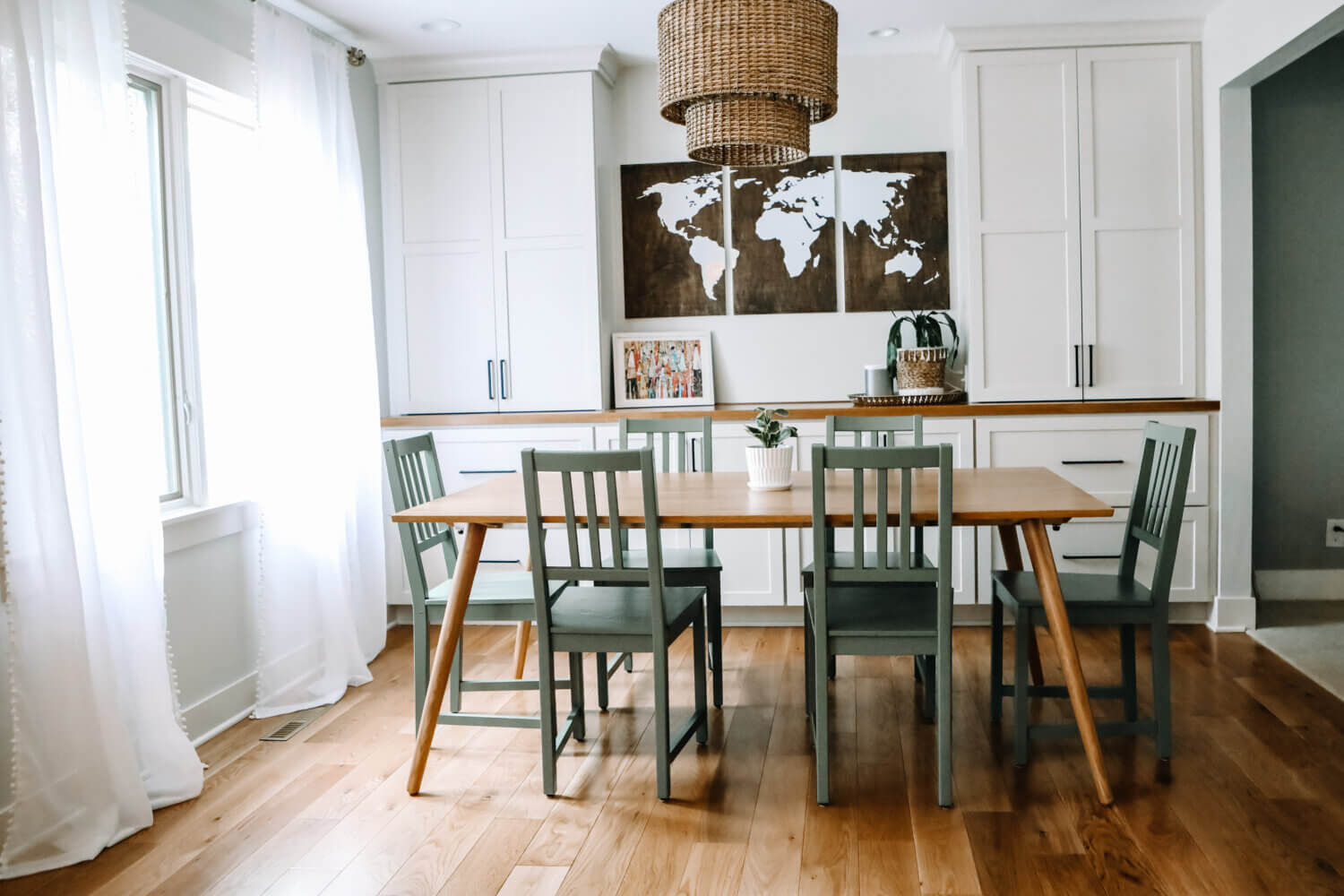 A straight on view of a dining room with built-in white painted cabinets with a wood top counter and 2 tall towers for additional dining room storage and space for homework supplies.