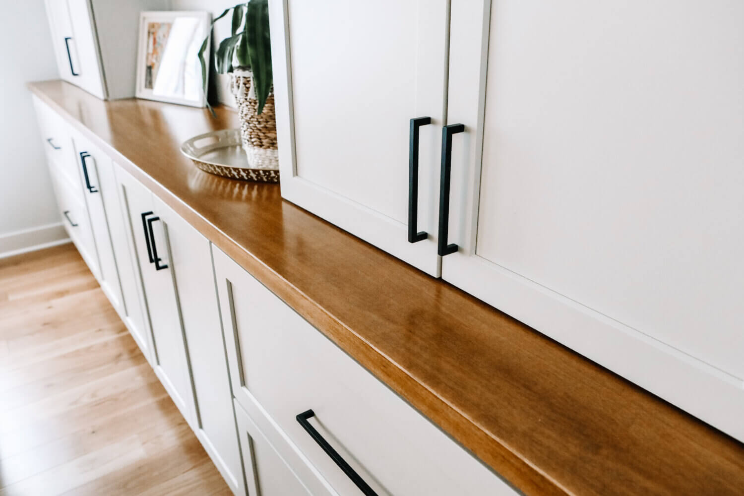 A close up of the wood top with a white painted cabinets in a dining room.