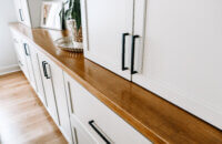 A close up of the wood top with a white painted cabinets in a dining room.