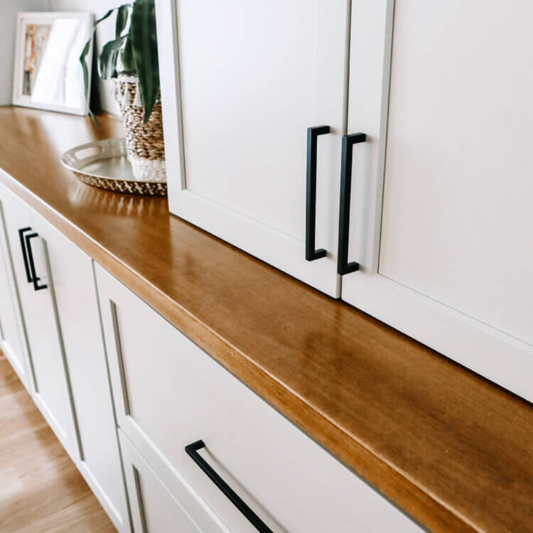A close up of the wood top with a white painted cabinets in a dining room.