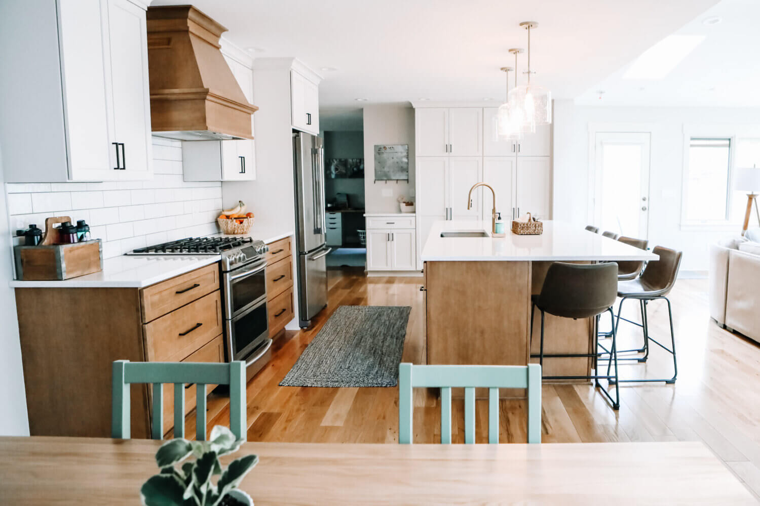 A view from the dining room of the kitchen in an open floor plan with two toned cabinets with white paint and light stained wood.