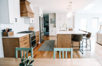 A view from the dining room of the kitchen in an open floor plan with two toned cabinets with white paint and light stained wood.