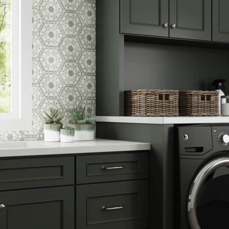 Dark olive green painted cabinets with a custom paint match finish using Dura Supreme's Personal Paint Match program to perfectly match the finish to Sherwin-Williams Rock Bottom paint color. A detailed hand-painted backsplash tile complements the color of the cabinetry throughout the room.