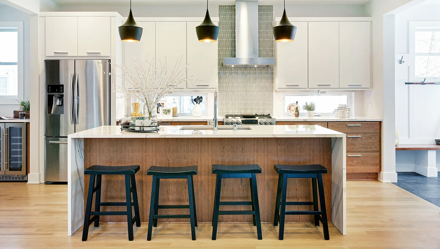 This Dura Supreme cabinetry is shown in the Toast stain on Red Oak on the kitchen island that also features a contemporary styled waterfall countertop. The perimeter cabinets are an off-white slab cabinet door with a modern look.