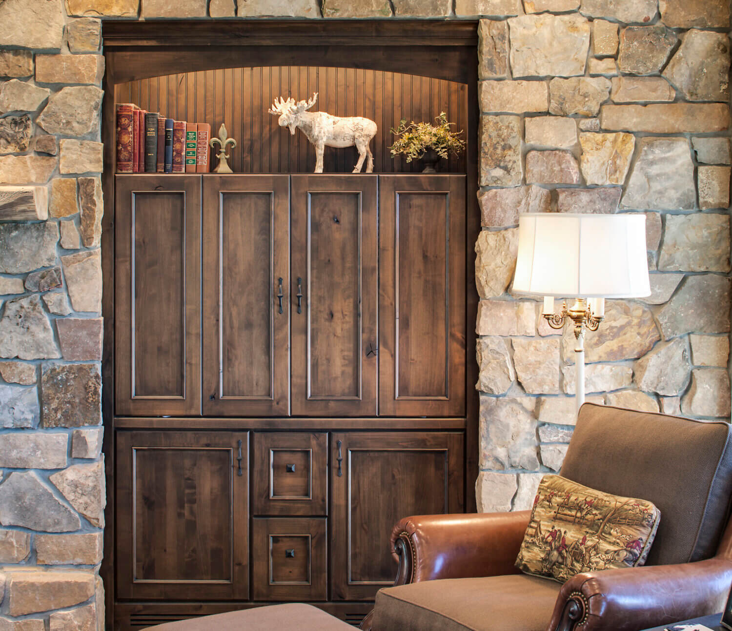 A built-in entertainment center surrounded by a decorative rock wall in a rustic living room design.