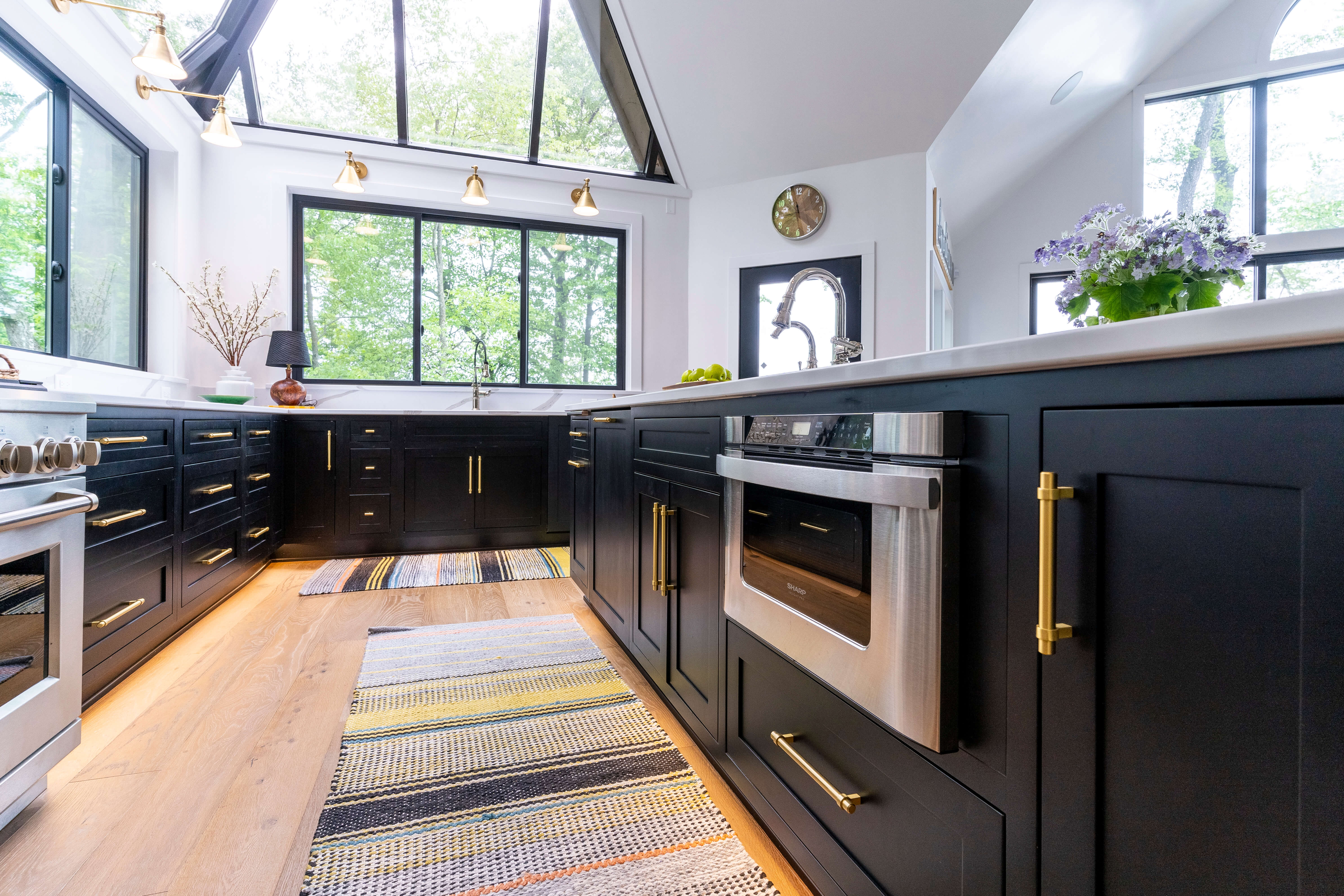 All black cabinets in a new home with vaulted ceilings, black framed windows, and bright white painted walls.