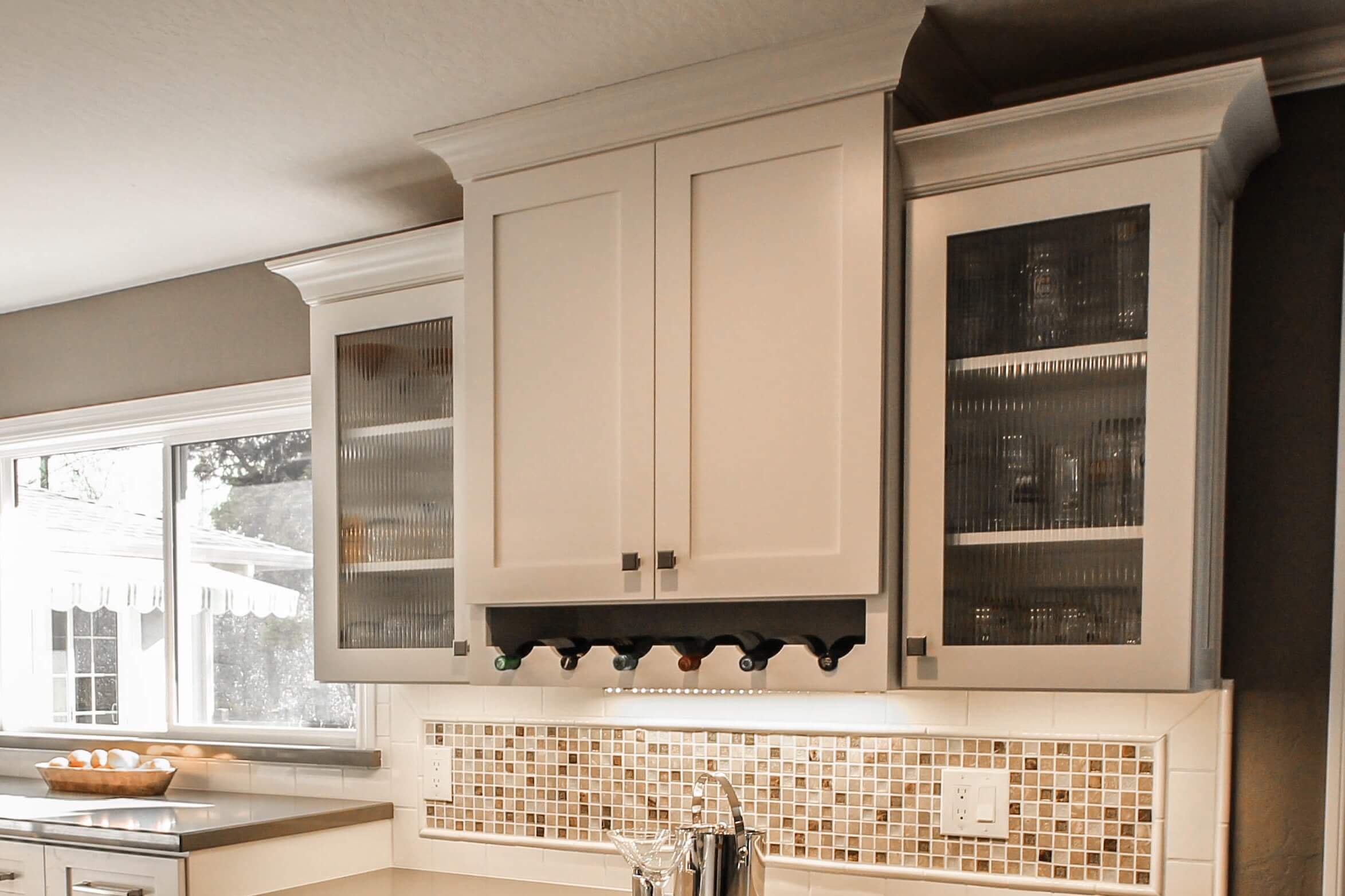 Glass cabinet doors around a wall cabinet wine rack with reeded glass inserts.