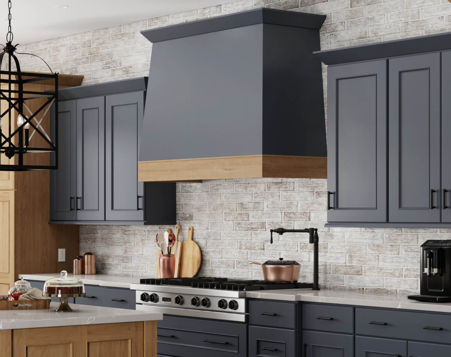 A close up of the two-toned wood hood and kitchen cabinets in a dark navy blue paint and light stained cherry wood.