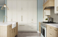 This dreamy lake house kitchen captures the home’s lake shore lifestyle with watery blue walls, shiplap ceilings, nature-inspired wood and white painted cabinetry, and natural stone accents. The kitchen design uses a natural off-white paint color contrasted by a light white washed stain on Quarter Sawn White Oak cabinets.