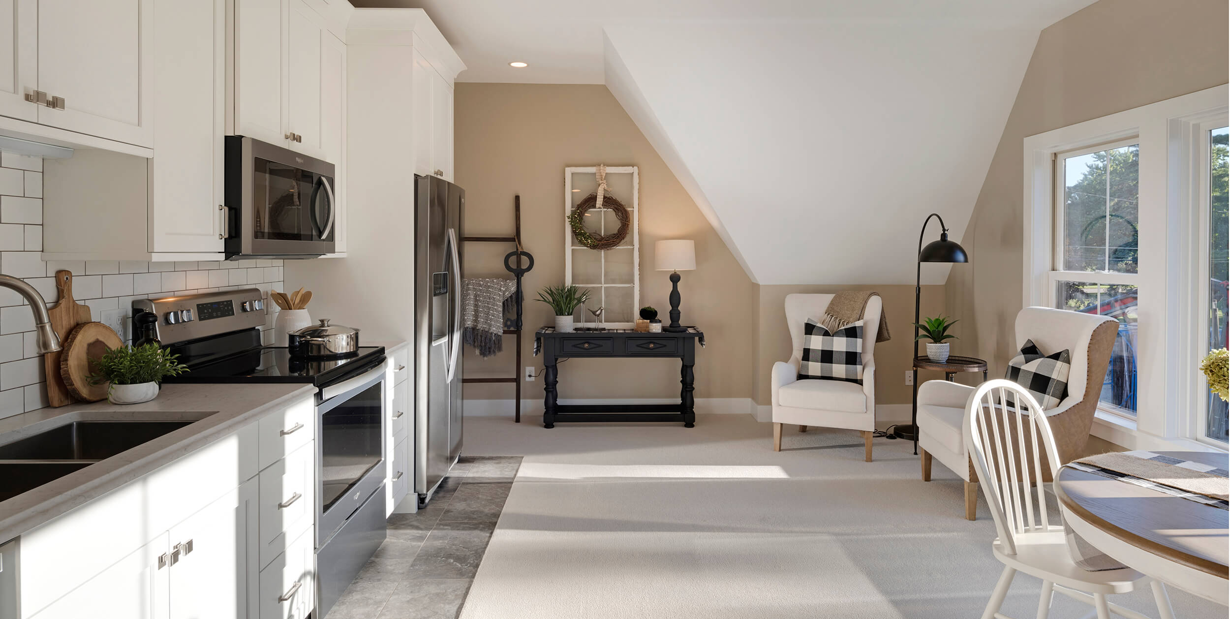 A single wall kitchen in a is the 2nd kitchen in this multi-generational home. Featuring white painted cabinets on one wall with windows on the opposite wall.