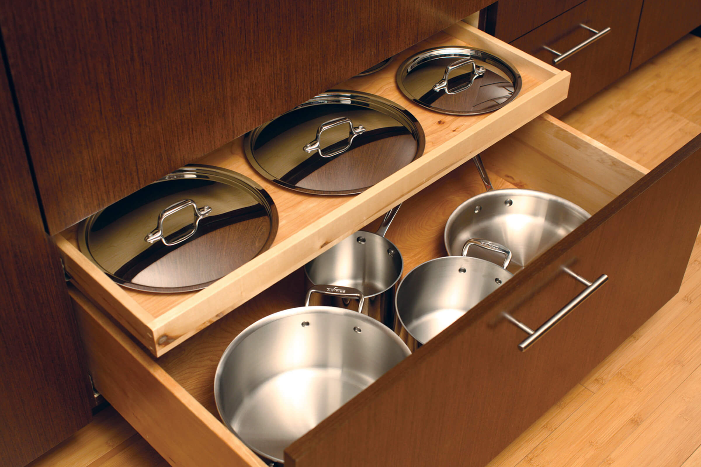 A shallow roll-out above a drawer works great for lid storage for pots and pans! This modern kitchen design has organized kitchen storage in deep cabinet drawers.