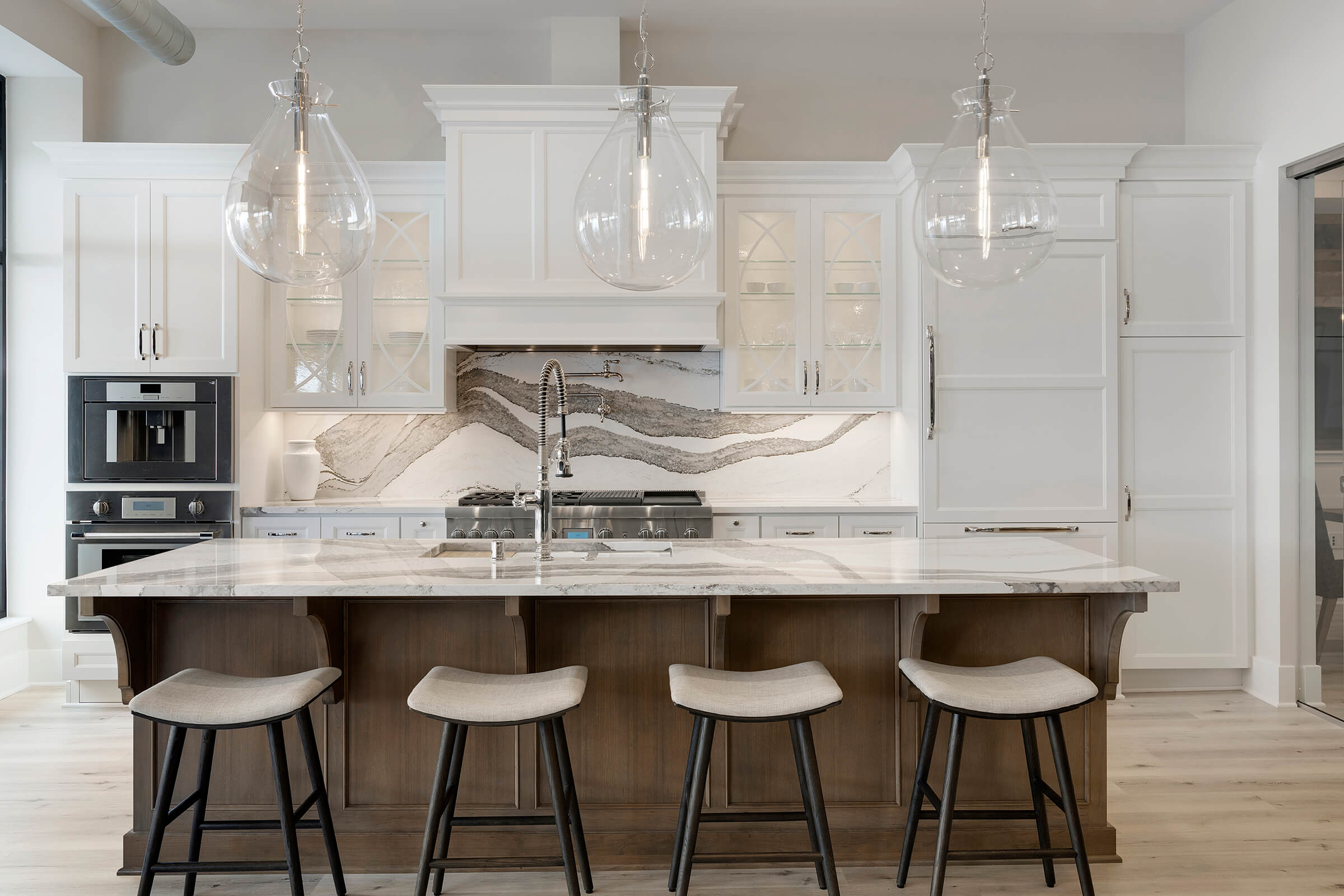 A stylish transitional style kitchen with a stained wood kitchen island and white painted cabinets on wood hood on the perimeter.