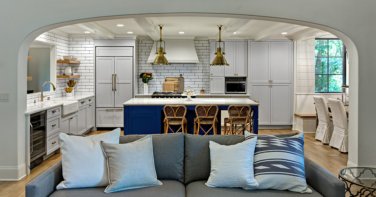 A modern nautical style kitchen design with light gray cabinets and a dark navy blue kitchen island.