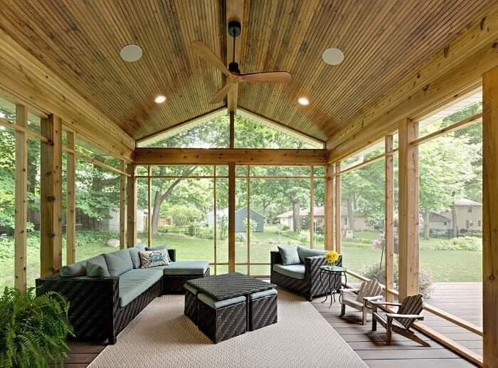 The sun room in the new custom home build in Minnesota. A cabin inspired style is created with the wood paneled ceiling and floor to ceiling wood window frames. It's the perfect place to enjoy the views of the backyard.