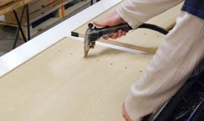 A cabinet maker drilling the dowell joints on a cabinet wall or end panel. 