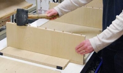 A cabinet maker at the factory adding the dowels to create the joinery for a new kitchen cabinet.