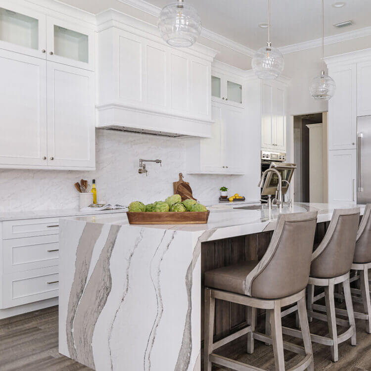 A beautiful kitchen remodel with low maintenance finishes and products. This kitchen features white painted cabinets with a delicate flat panel door style with a dark stained knotty alder kitchen island with a dramatic mitered waterfall kitchen island countertop in a white quartz.