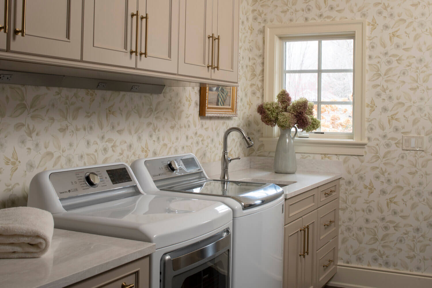 An off-white and beige laundry room design with Dura Supreme cabinets.