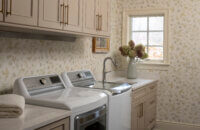 An off-white and beige laundry room design with Dura Supreme cabinets.