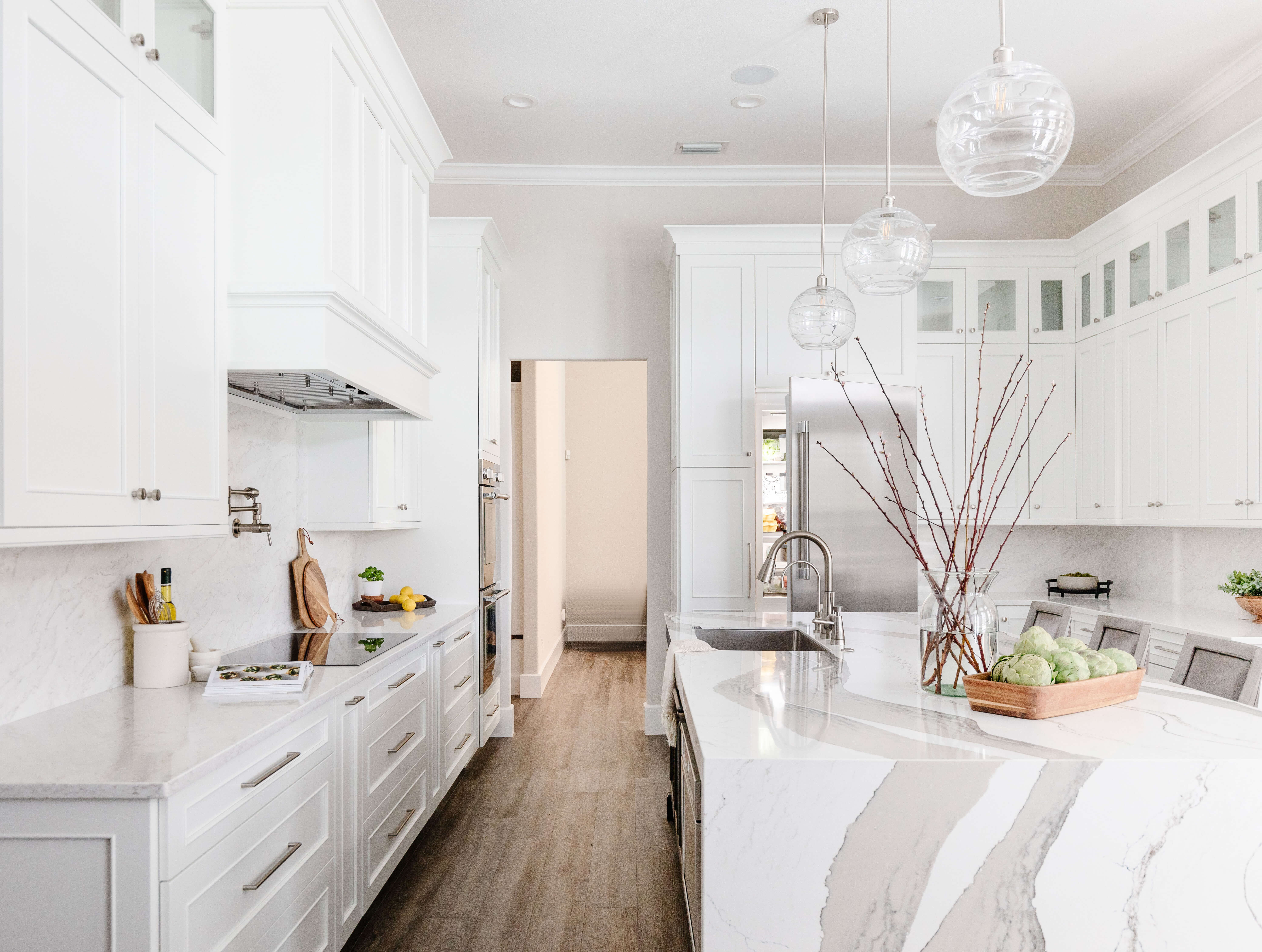 A white painted kitchen with a knotty alder kitchen island and quartz countertops. A white painted wood hood makes a beautiful focal point above the cooktop.