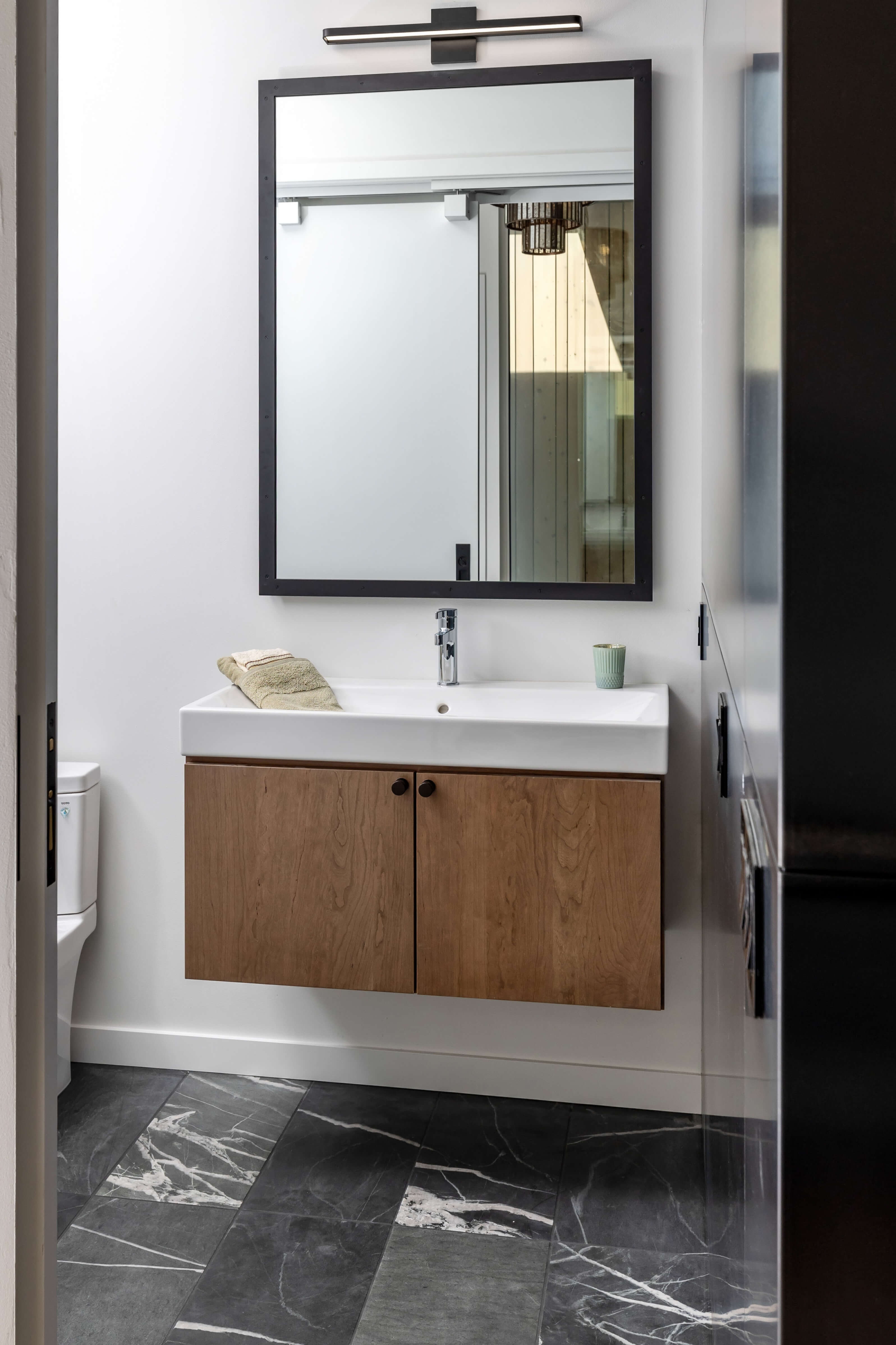 A small powder room feels larger with a small floating vanity in a stained cherry wood. What is a floating vanity? How do I make my bathroom feel larger?
