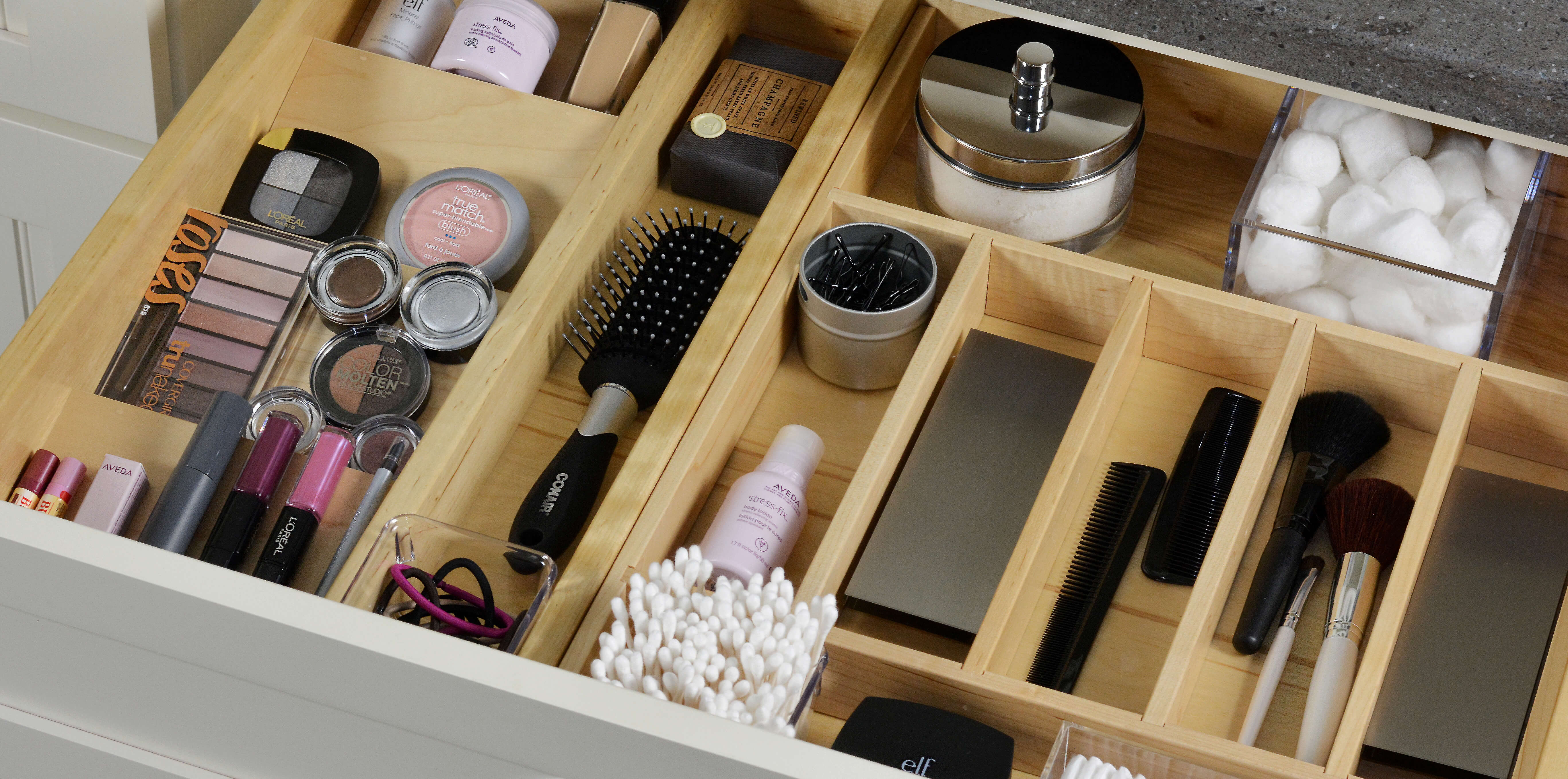 A neatly organized bathroom drawer using a drawer rack, a cutlery divider, and partitions to organize and store bathroom supplies and cosmetics.