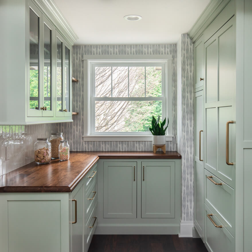 A light green painted butler's pantry with a mint green paint color on the kitchen cabinets and antiqued bronze hardware.