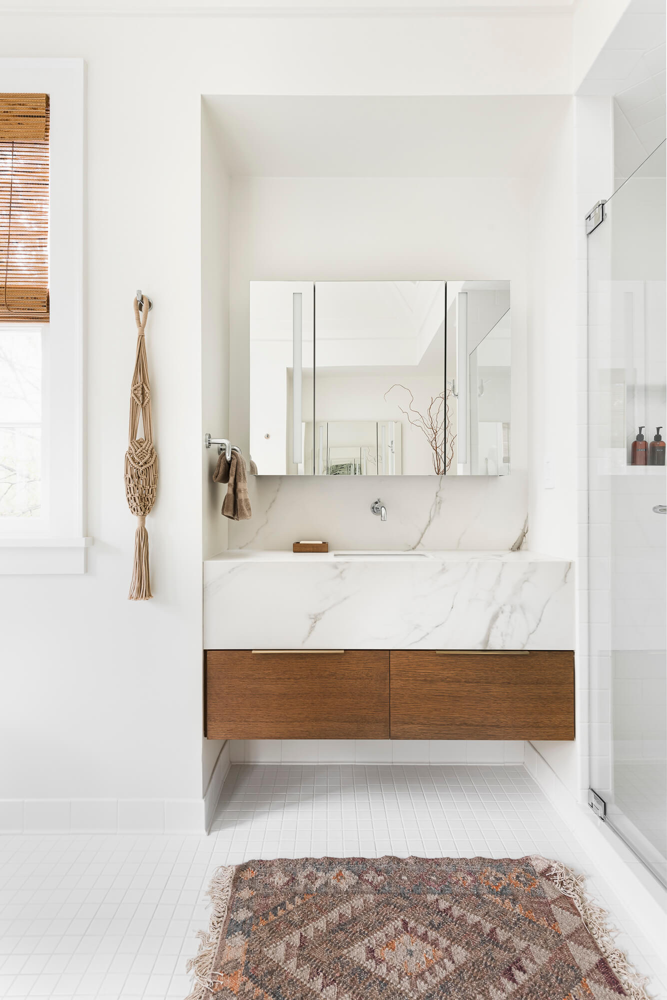 An elegant floating bathroom vanity with two deep drawers and a very think and tall vanity countertop in a white quartz material. The inset in the wall framed the vanity and mirror.