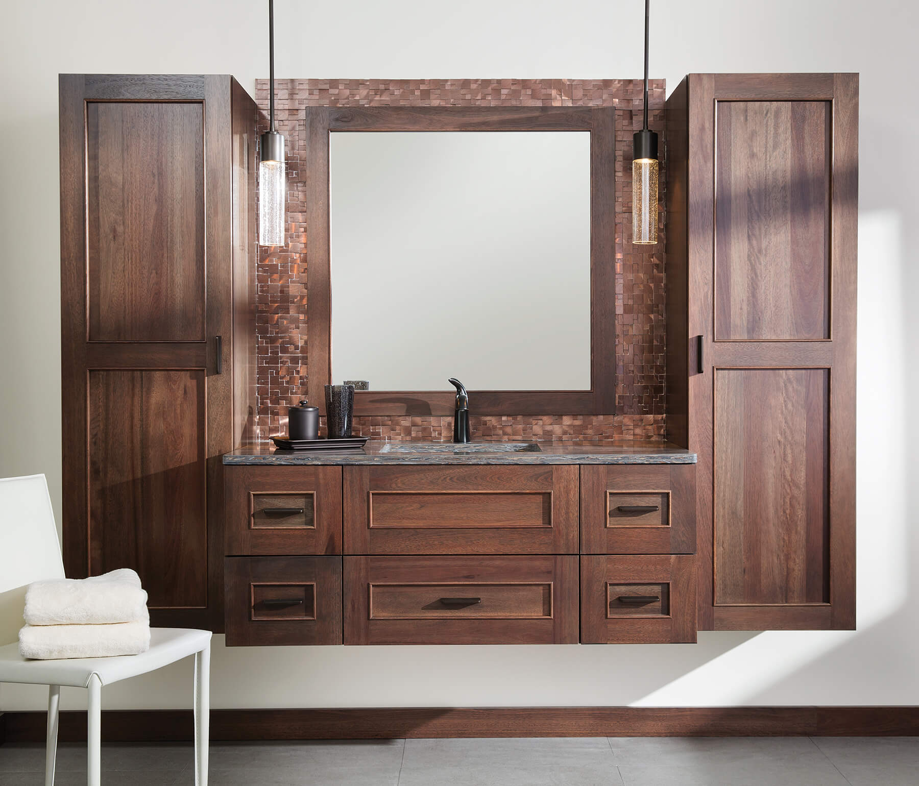 Floating vanities are a favorite look for small bathrooms to impart an open, airy and expansive feel. For this bath, rich bronze and copper finishes are combined for a stunning effect. A centered sink includes convenient drawers on both sides of the sink for powder room storage, while two wall-hung linen cabinets frame the vanity to create a sleek, symmetric design.