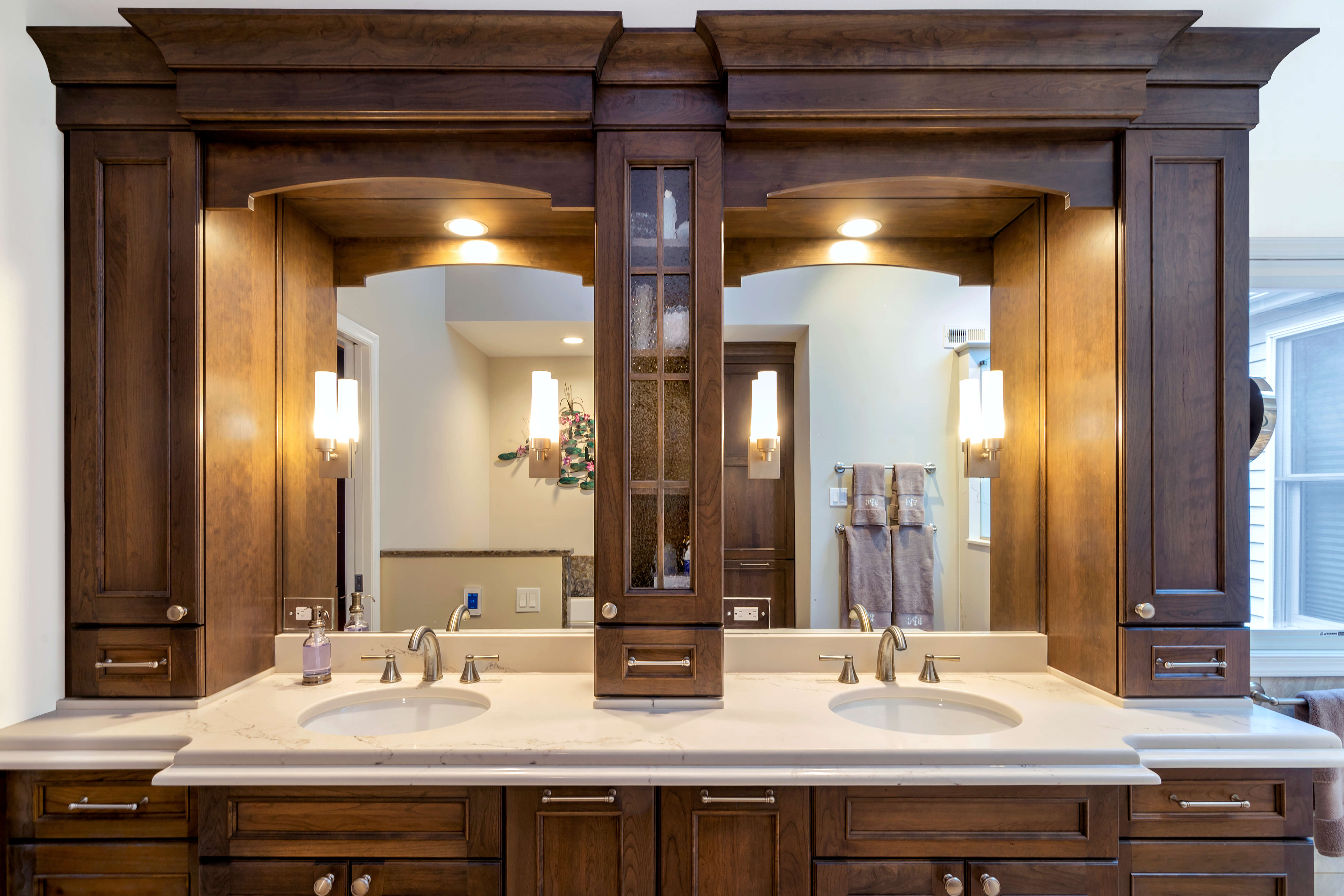 A double sink bathroom vanity with divided mirrors and a tall tower in between.
