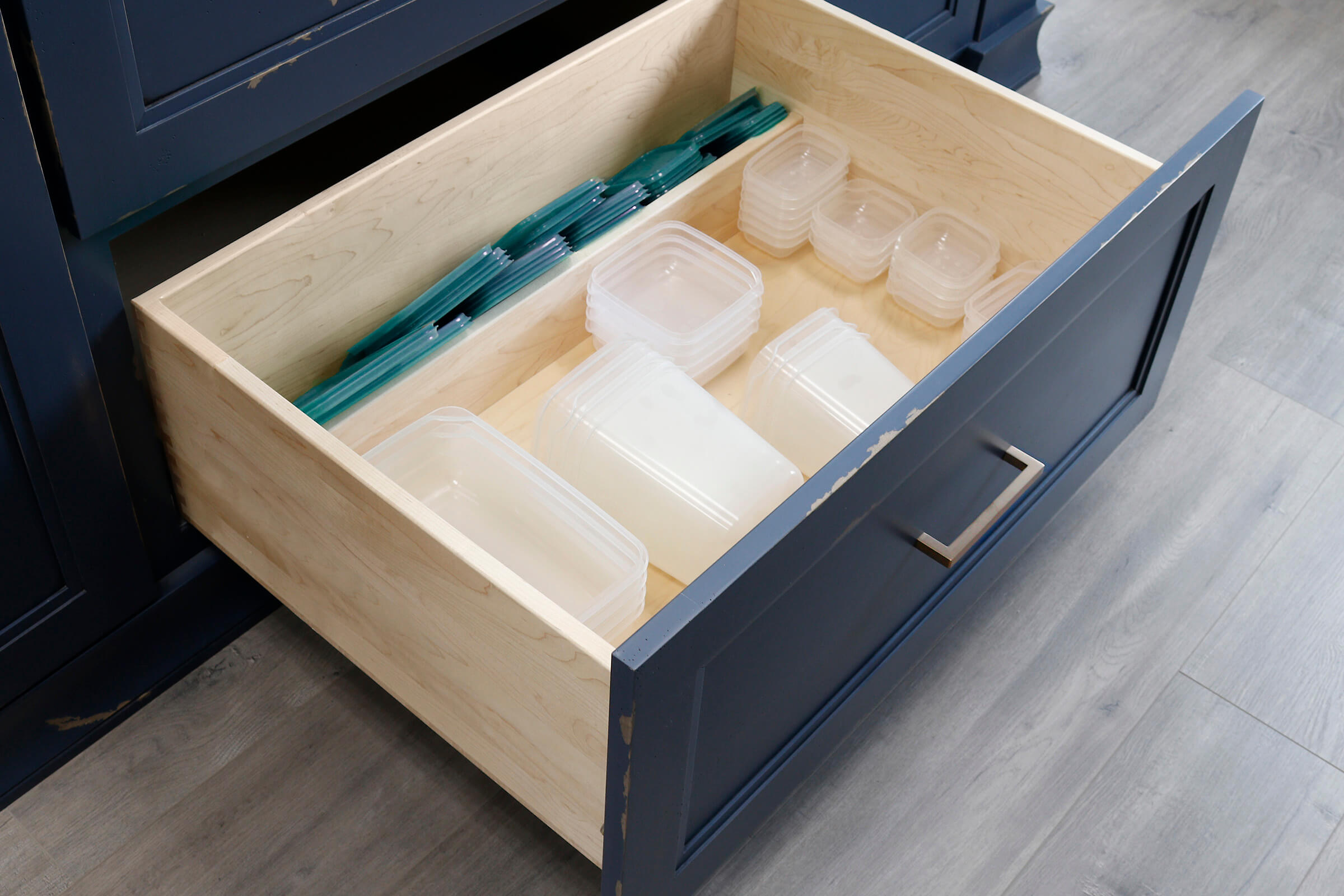 A Lid Storage Partition at the back of a wide, deep drawer neatly stores plastic containers and lids in a neatly fashion.