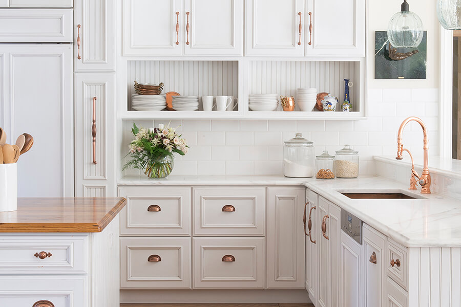 A traditional French Country style kitchen with bright white painted cabinets and an open shelf.
