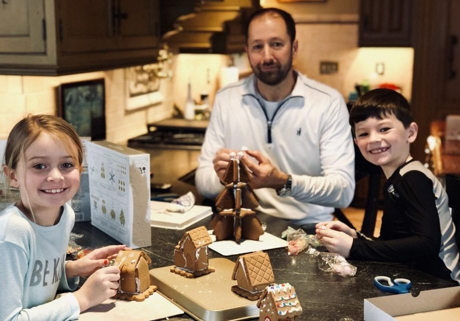 A father and his two children enjoy time as a family in their newly remodeled kitchen as they make gingerbread houses for the holidays.