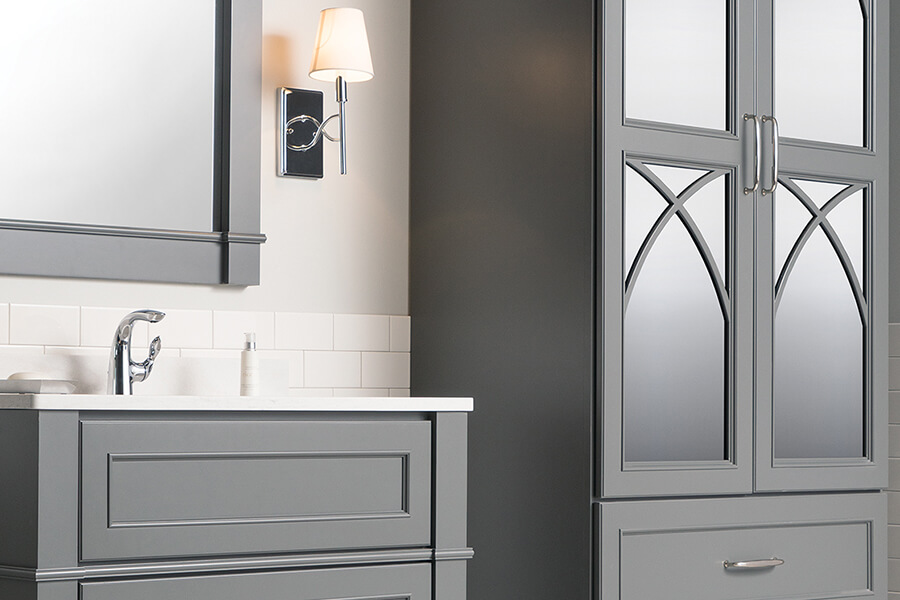 A gray bathroom design with trendy glass cabinet doors.