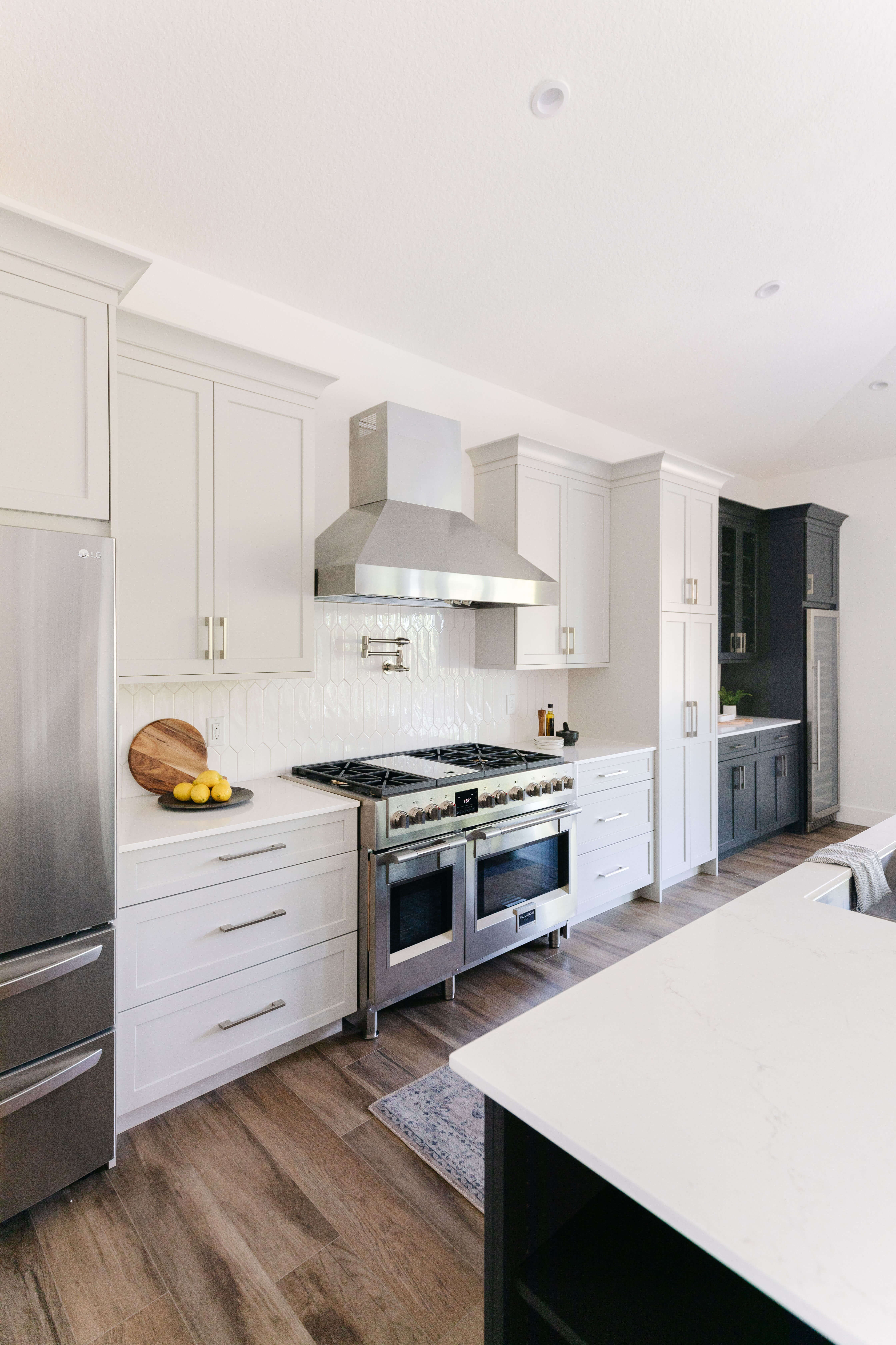 A white mid-century modern kitchen design with a black pained kitchen island and beverage center nook.