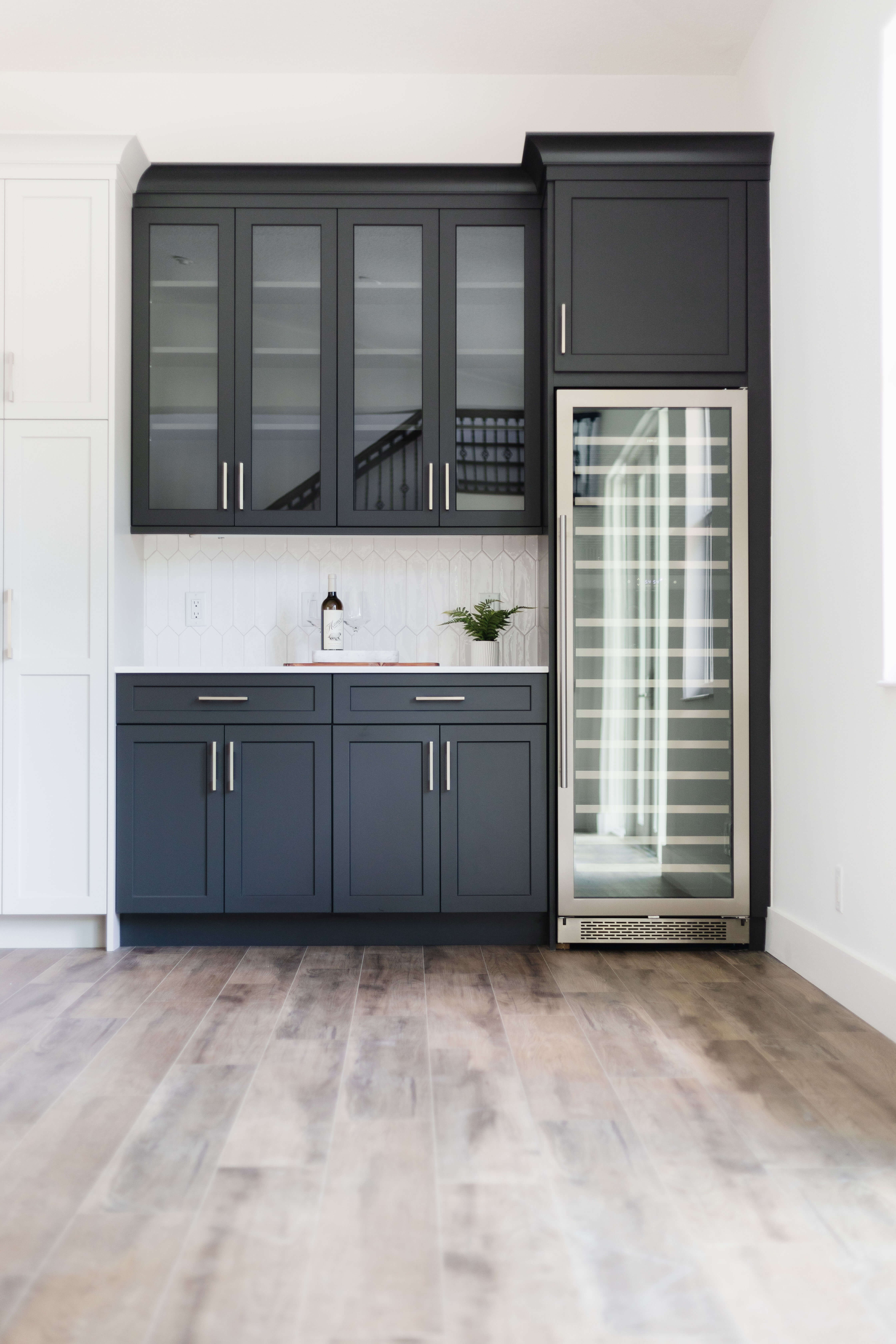 The dark gray, black painted cabinets with a wine & beverage fridge and buffet table space.