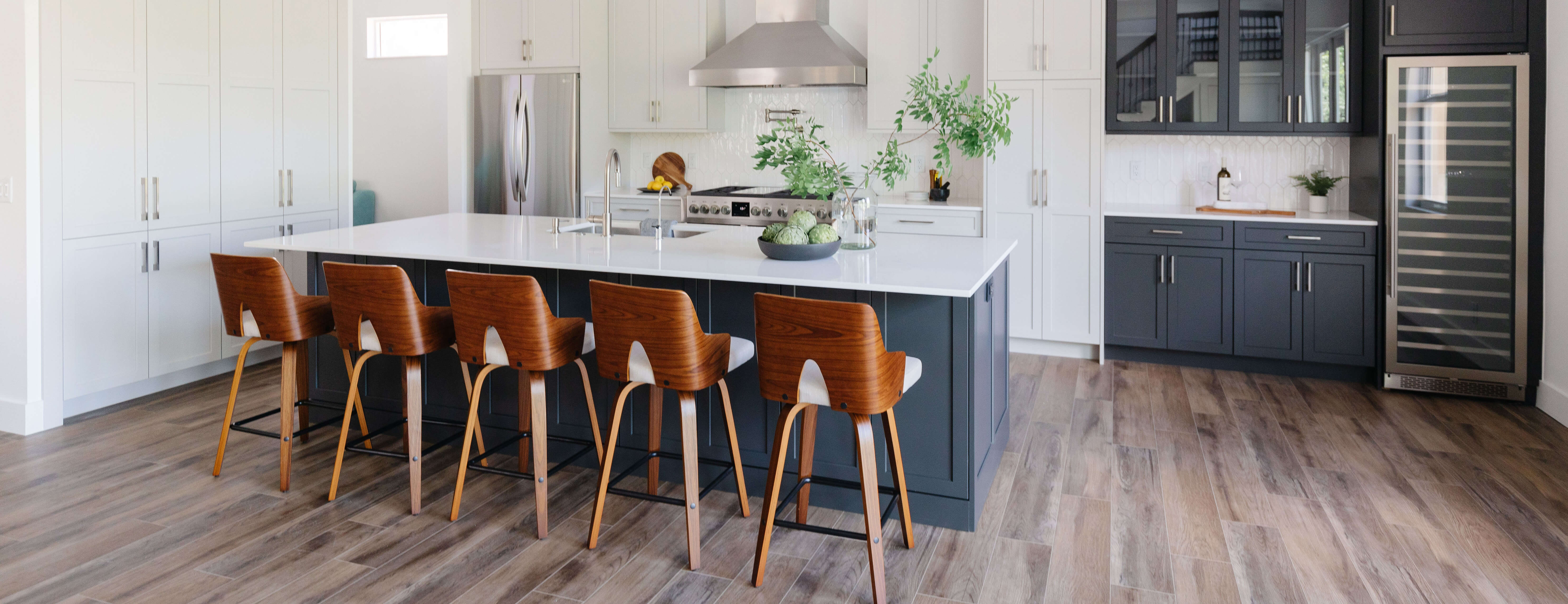 A mid-century modern kitchne reno with a long black painted kitchen island and white painted cabinets from Dura Supreme.