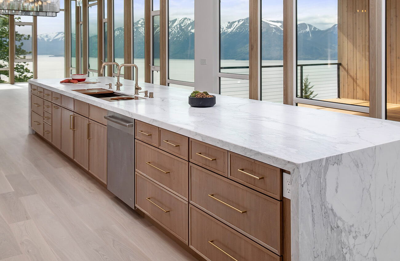 High quality wholesale cabinets for dealers and designer showing a long kitchen island with a modern shaker door style with white oak kitchen cabinets.