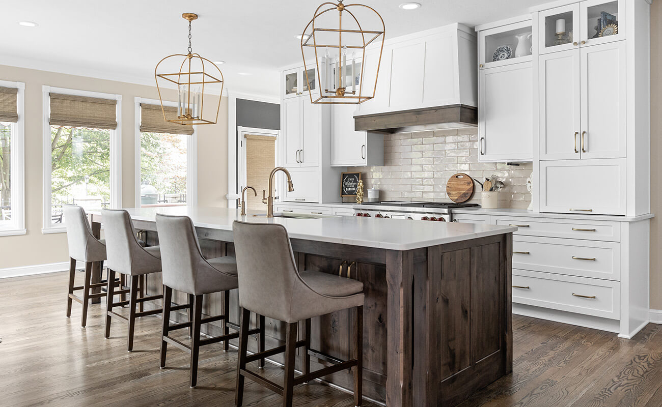 A modern farmhouse kitchen with dark stained knotty alder cabinets and white painted cabinets with a grand wood hood.