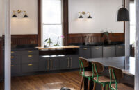 A modern kitchen with black painted cabinets that have a modern shaker cabinet door style.