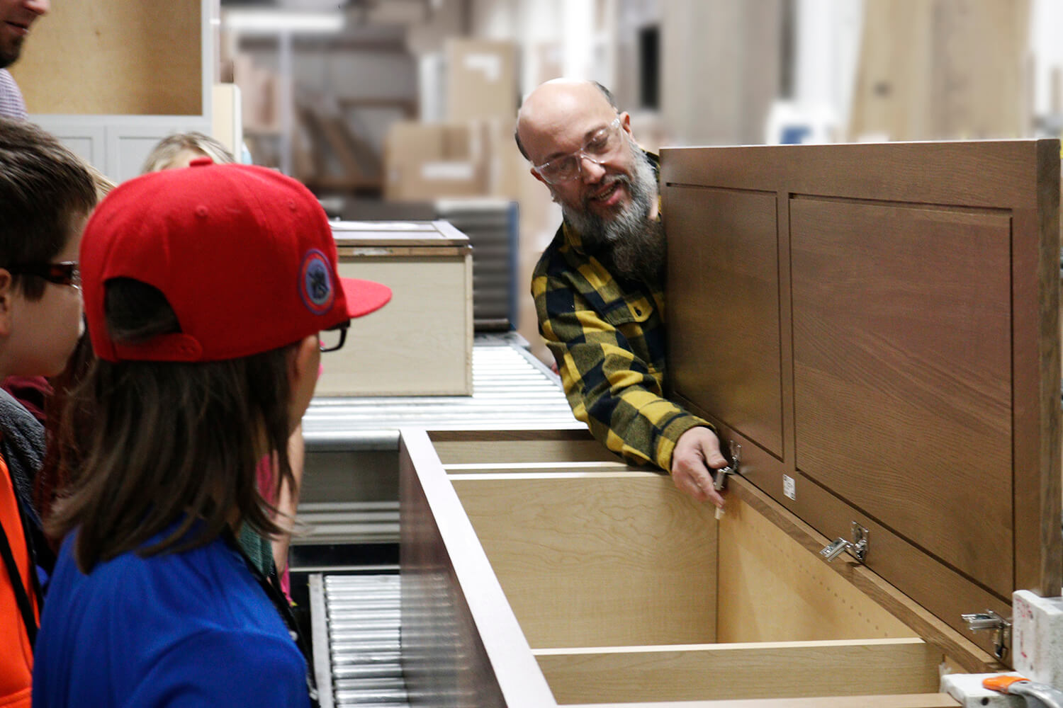 A cabinet maker teaching students about cabinet manufacturing during a factory tour for 5th graders.