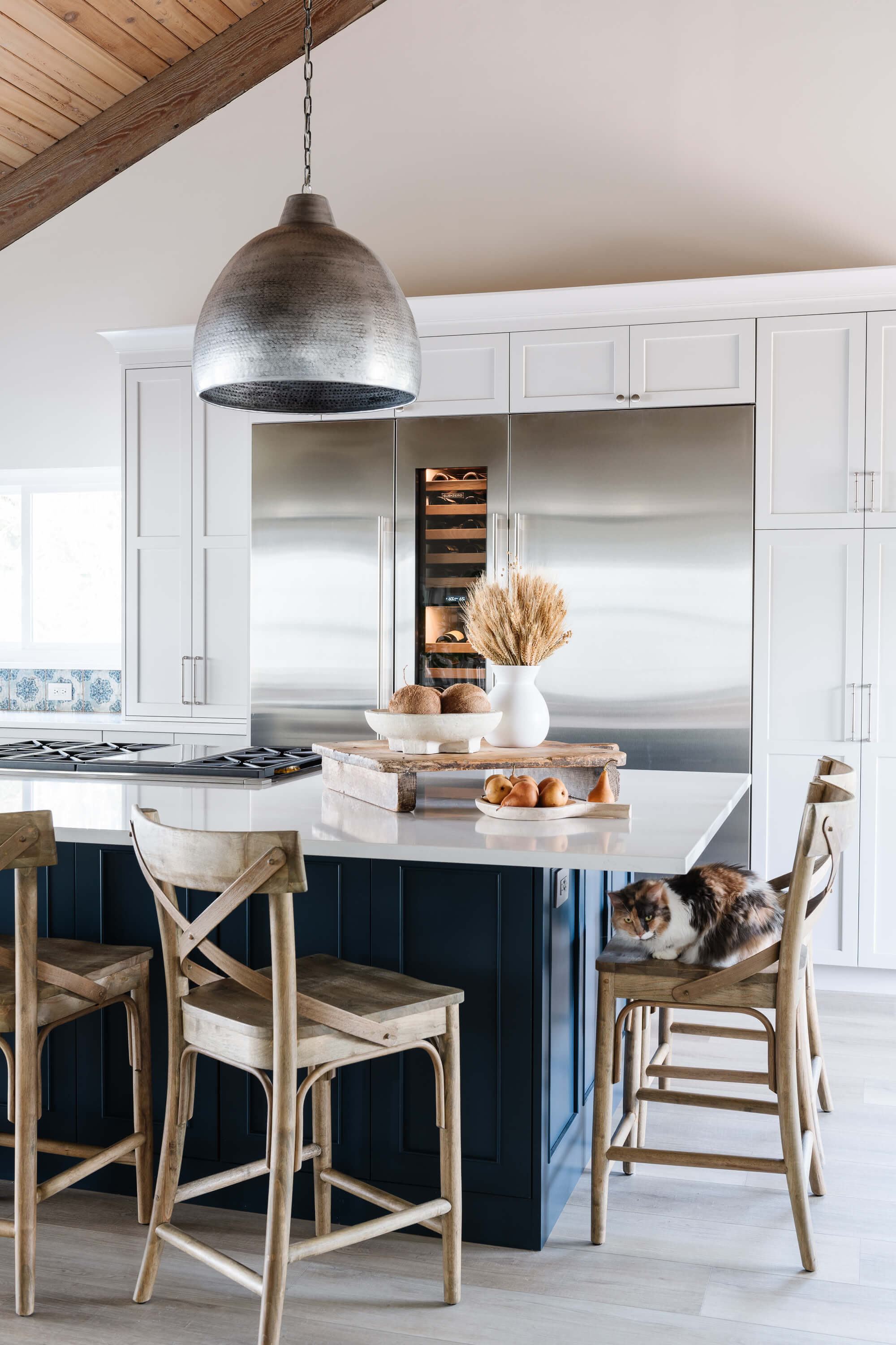 A beautiful kitchen design with white cabinets for the perimeter and dark, navy blue painted kitchen island.