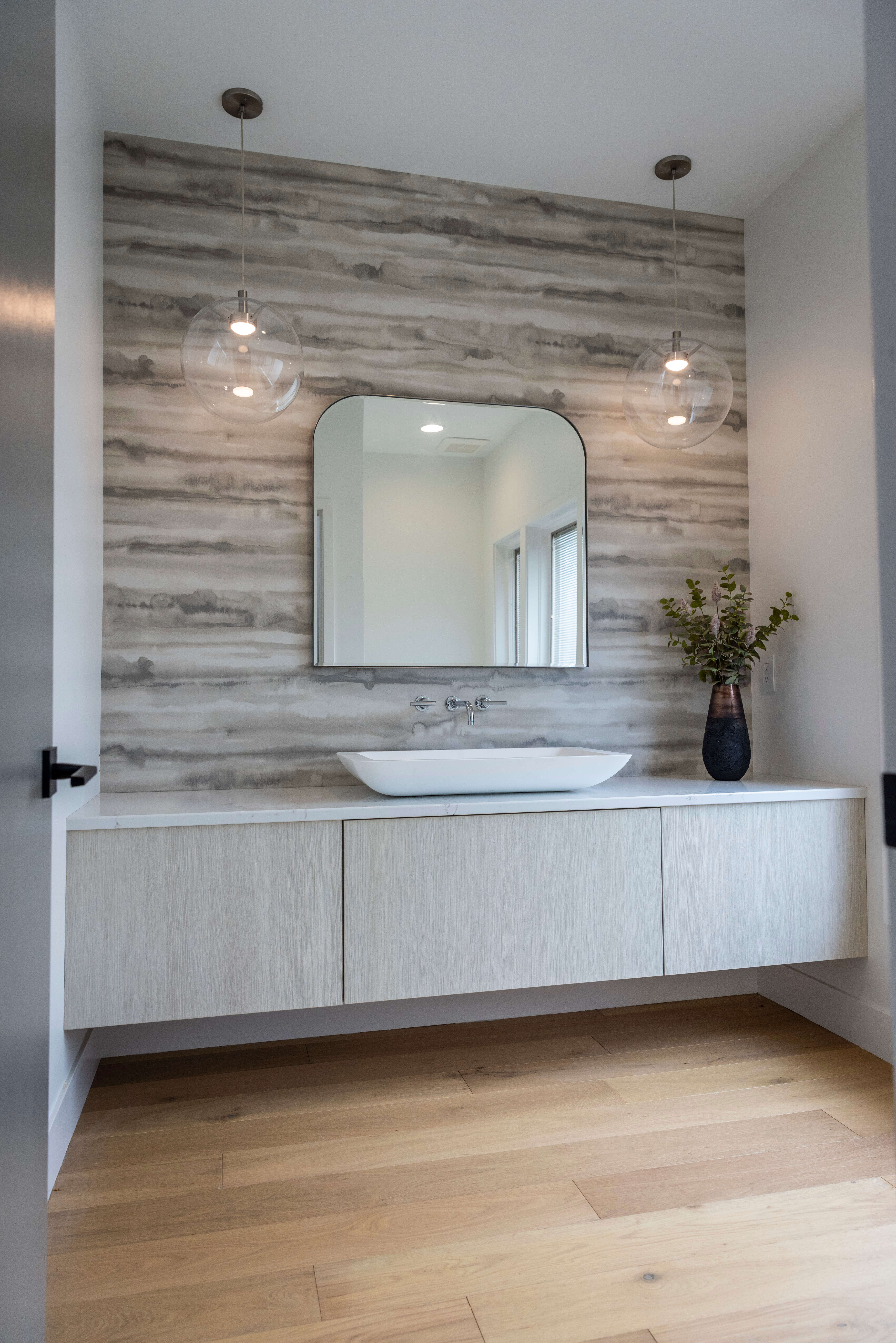 A soft contemporary bathroom design with light stained wood and beige finishes with a slab styled floating vanity cabinet.