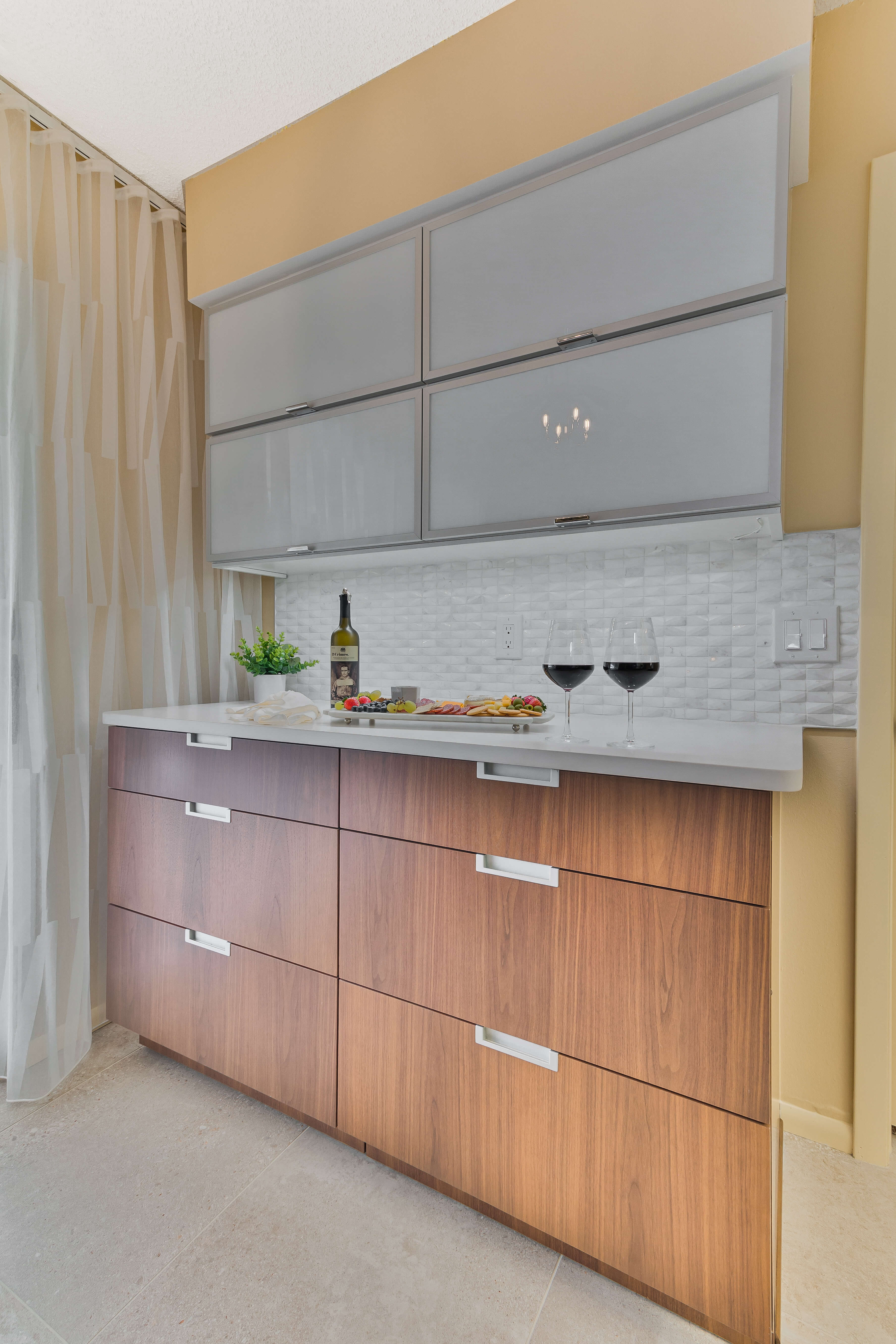 A beverage center in a Mid-Century Modern styled kitchen featuring wood slab cabinet doors with integrated hardware pulls paired with contemporary aluminum framed accent doors.