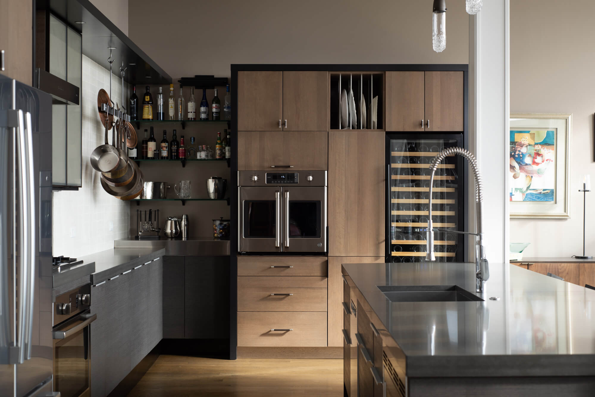 An urban loft style kitchen design with two tone slab cabinets mixing a dark exotic shale veneer with light stained cherry wood.