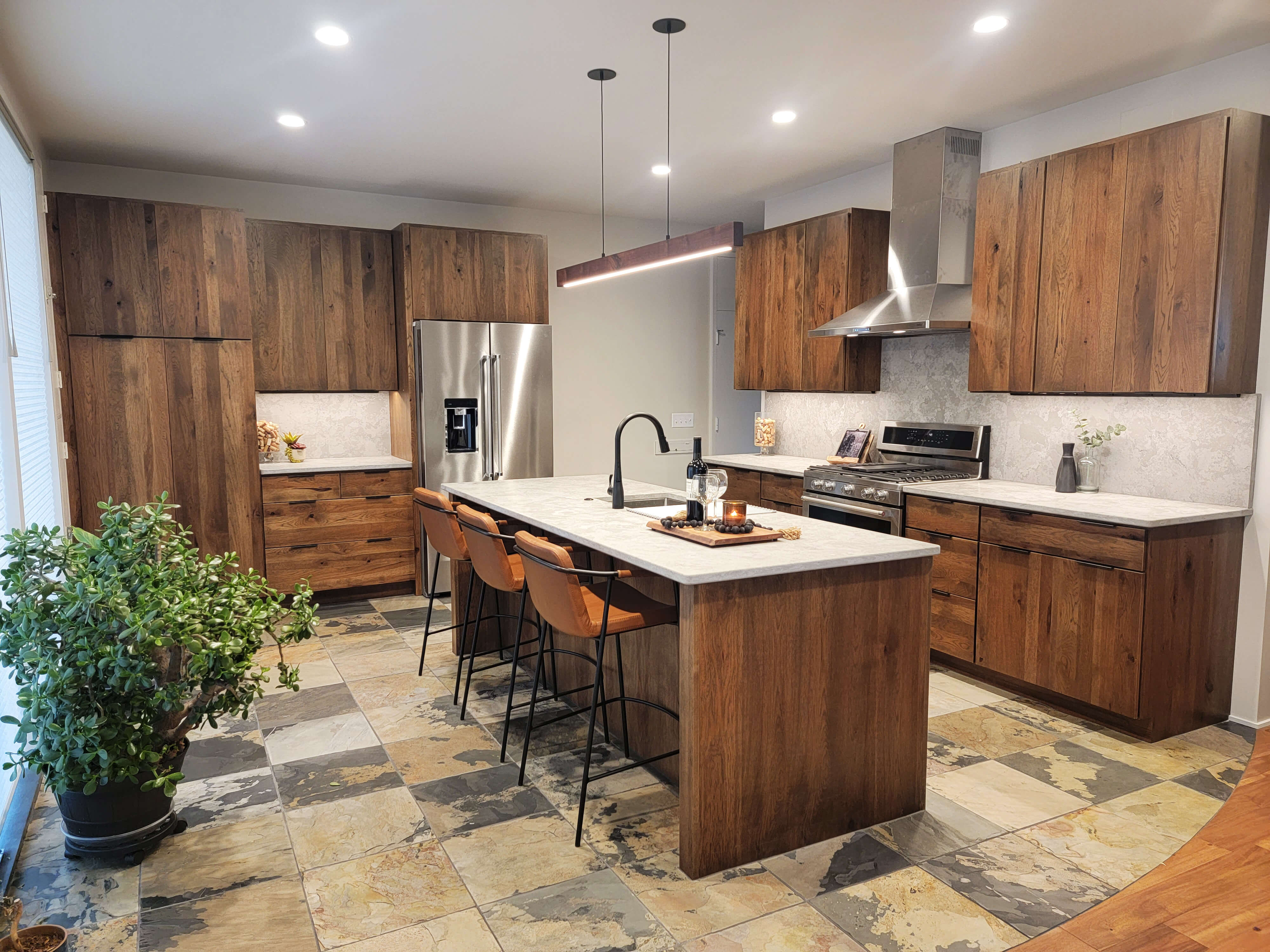 A modern rustic styled kitchen design with Rustic Hickory slab cabinet doors with a medium to dark stained finish.