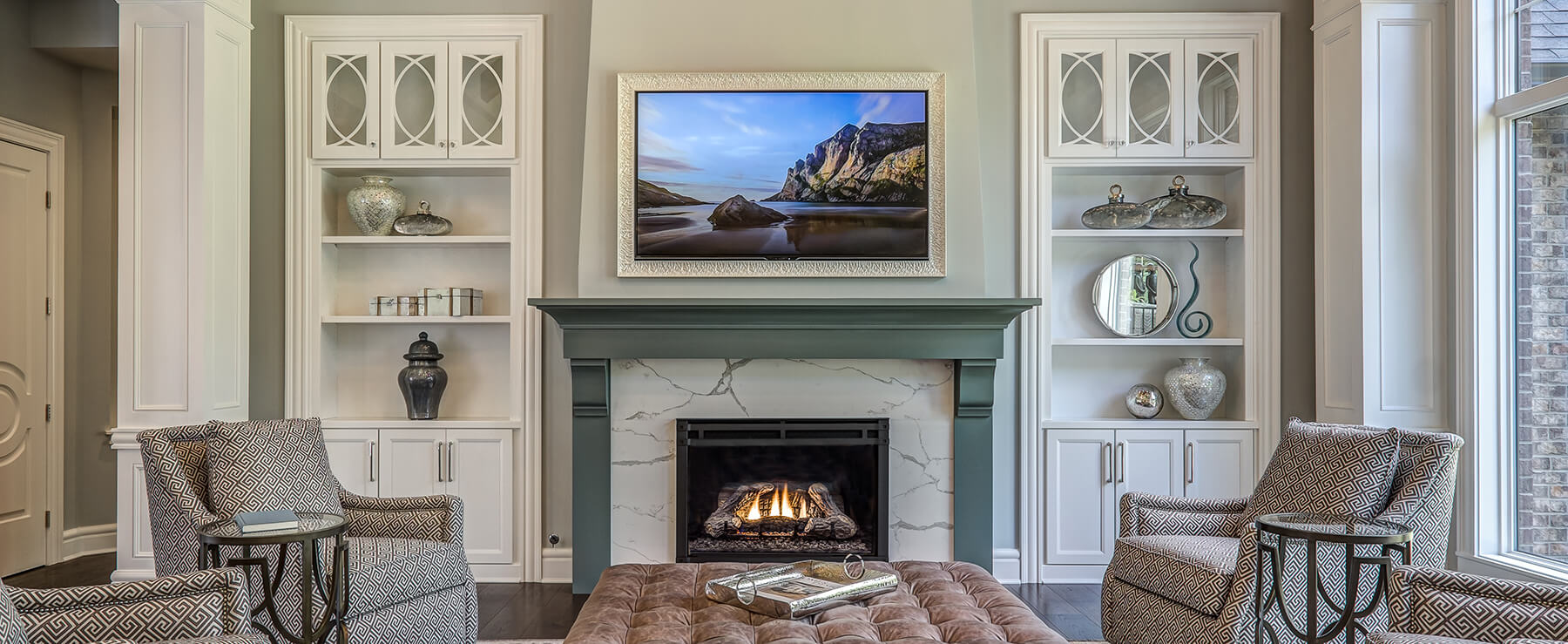 A green painted fireplace mantel surrounded by white painted bookcases and entertainment center cabinets.